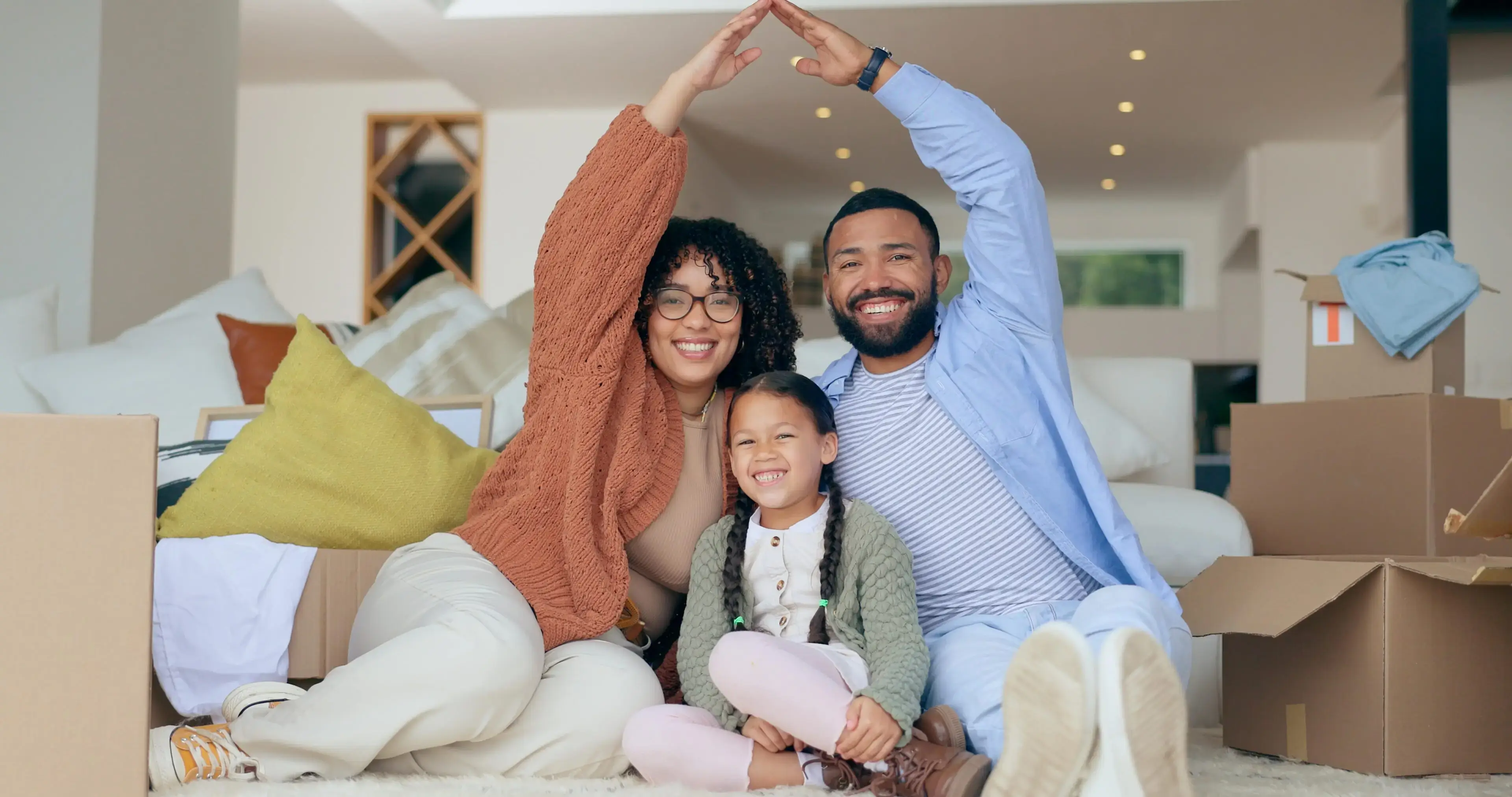 A family sitting on the floor with their hands in the air.